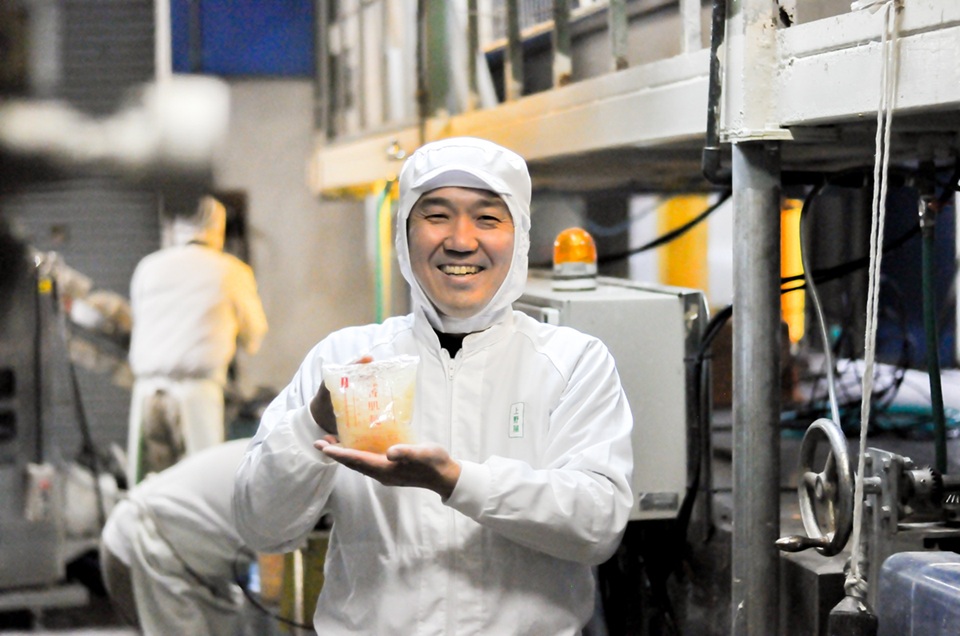 工場で製品を手に持つ笑顔の技術者