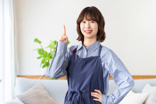 指を指して微笑むエプロン姿の女性
