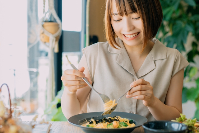 カフェでパスタを楽しむ微笑む女性